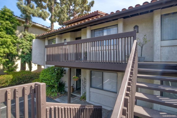Front view of a two-story building with a staircase and wooden railings.