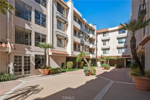 Exterior view of a multi-story residential building with balconies and a courtyard.