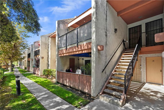 Front view of a multi-story apartment building with outdoor staircases and balconies.