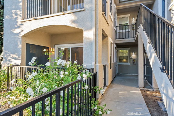 View of a multi-story apartment building entrance with balconies and a walkway.