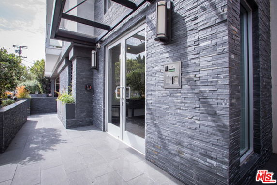 Front view of a modern building with stone exterior and glass doors.