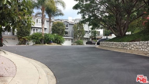 Front view of residential houses with garages and surrounding landscape.