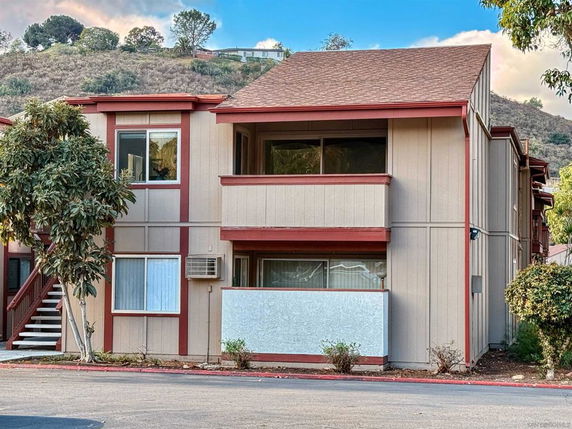 Front view of a two-story building with a covered balcony and an air conditioning unit.