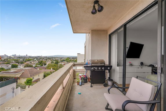 Balcony with seating and a grill overlooking a residential area.