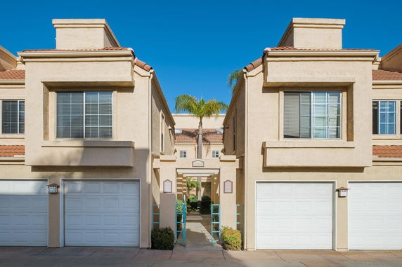 Front view of a townhouse with garages and large windows.