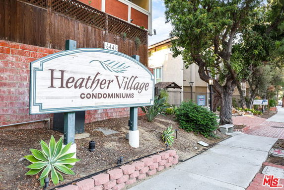 Signage for Heather Village Condominiums in front of building.