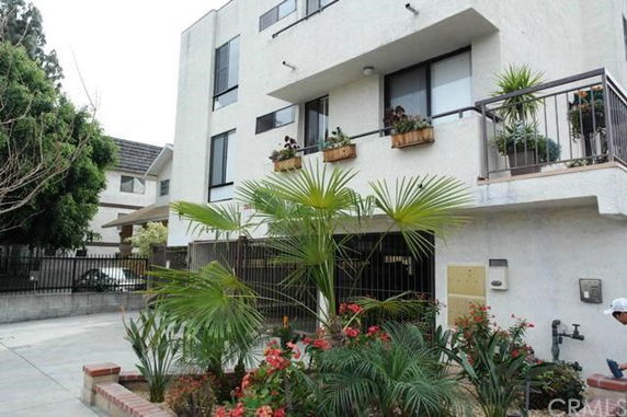 Front view of a multi-story building with balconies and potted plants.