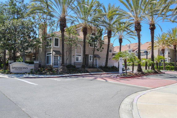 Front view of a multi-story residential building with palm trees.