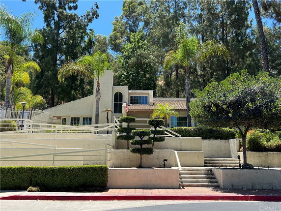 Front view of a two-story house with a sloping roof and trees in the background.