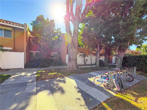 Front view of a two-story house with a white fence and bicycles parked outside.