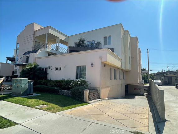 Front view of a modern multi-story building with balconies and a driveway entrance.
