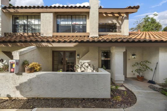 Front view of a two-story house with a tiled roof and a small courtyard.