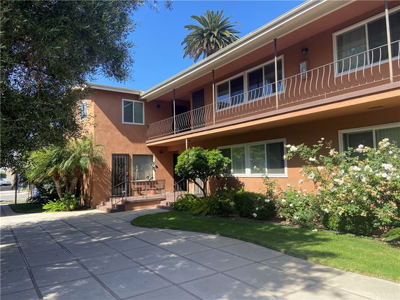 Front view of a two-story house with a balcony and garden.