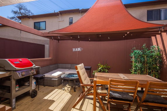 Patio with outdoor seating, grill, and sunshade canopy.