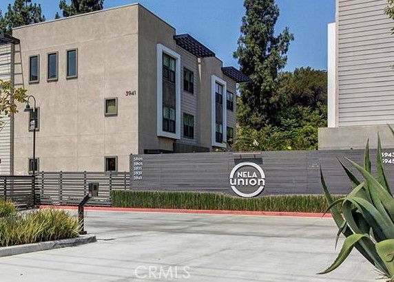 Front view of a modern multi-story apartment building with a gated entrance.