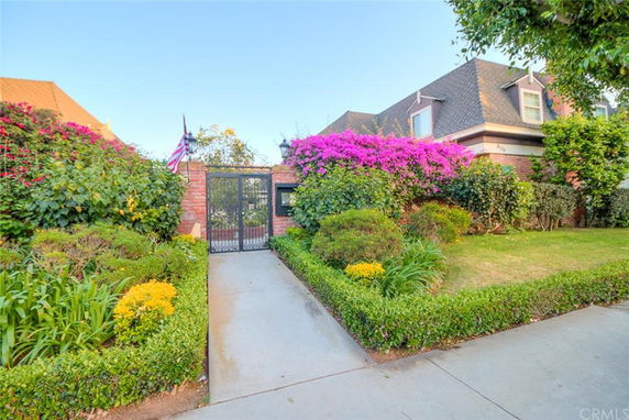 Front view of a house with a well-maintained garden and a gated entrance.
