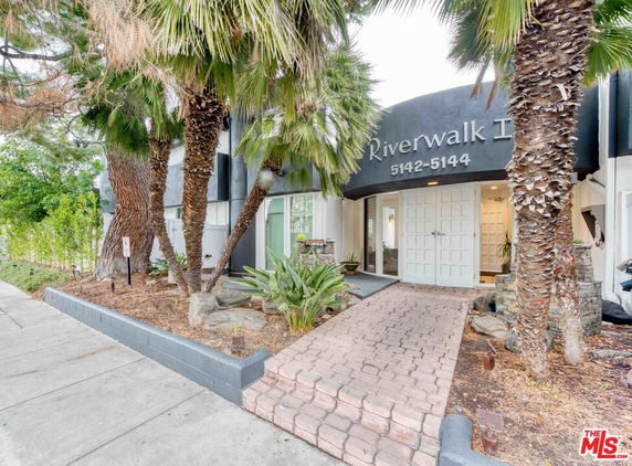 Front view of a building with arched entrance and palm trees.