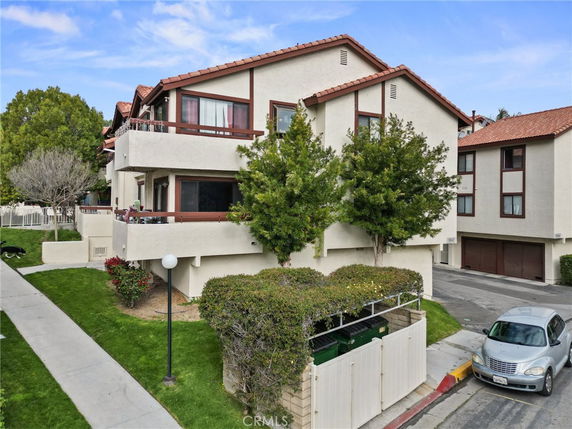 Front view of a multi-story house with balconies and red-tiled roof.