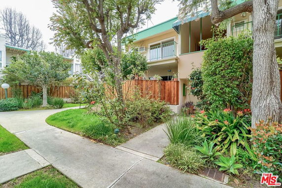 Front view of a two-story house with a balcony and garden.