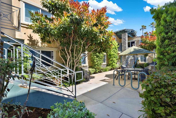 Exterior view of an apartment complex with greenery and outdoor seating.