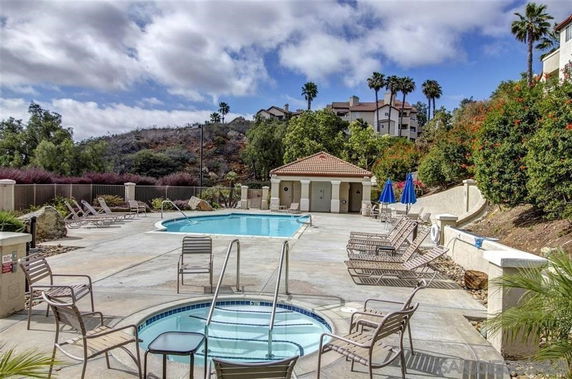 Outdoor swimming pool area with lounge chairs and umbrellas.