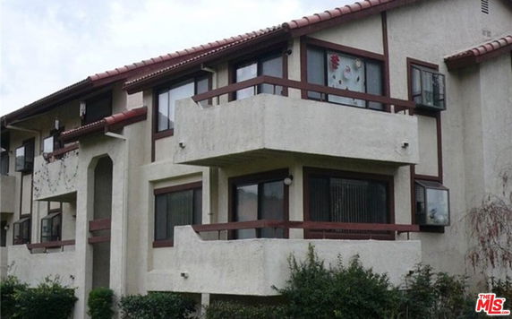 Front view of a multi-story residential building with balconies and red-tiled roofs.