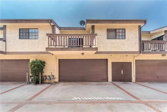 Front view of a two-story house with a balcony and multiple garages.