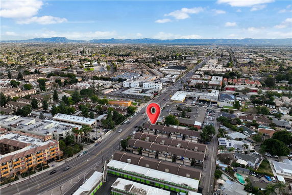 Aerial panoramic view of a cityscape with roads, buildings, and distant mountains.