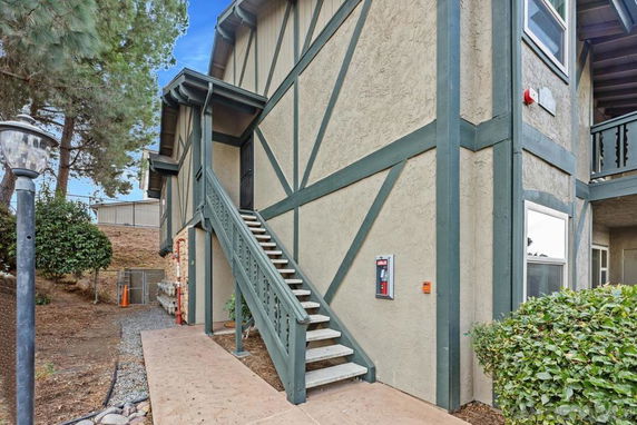 Side view of a multi-story building with external staircase and wooden accents.