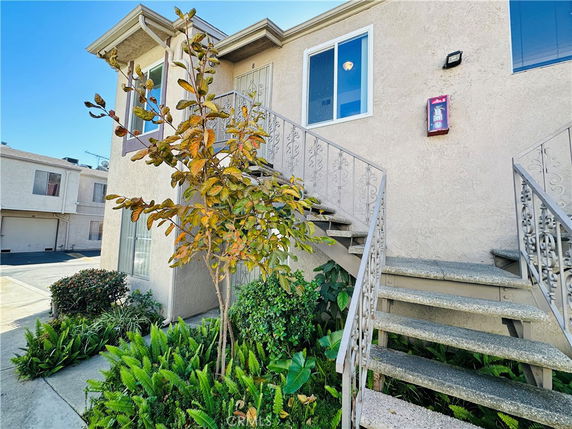 Front view of a two-story building with exterior stairs and plants.