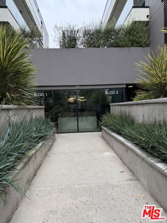 Entrance view of a building with labeled glass doors BLDG 1 and BLDG 2.