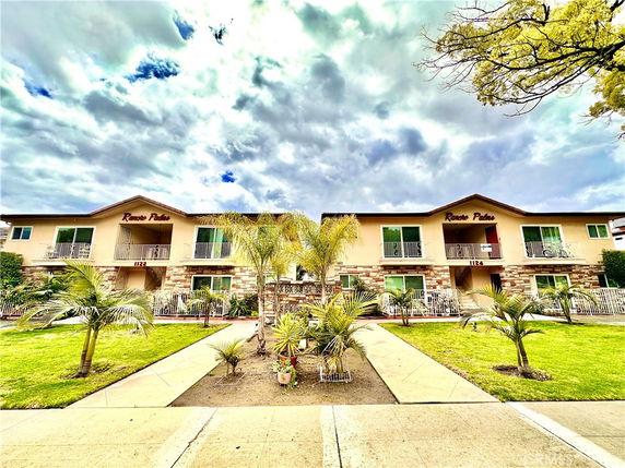 Front view of a two-story apartment building with balconies and the name 'Rancho Palms' displayed at the top.