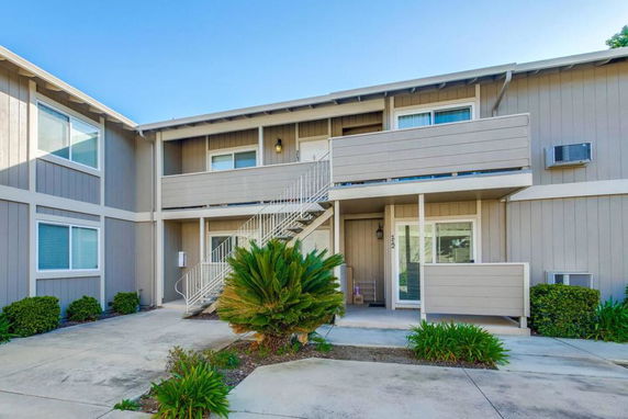 Front view of a two-story residential building with balconies and outdoor staircase.