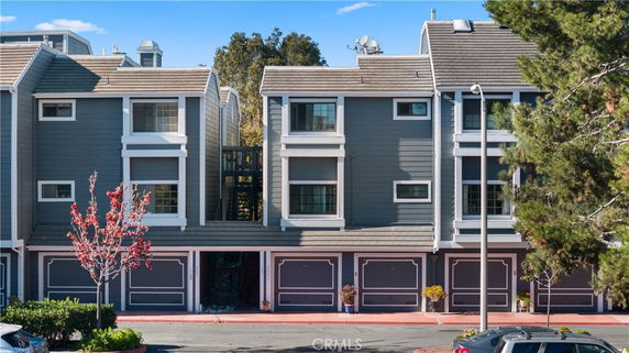 Front view of a multi-story townhouse with garages on the ground level.