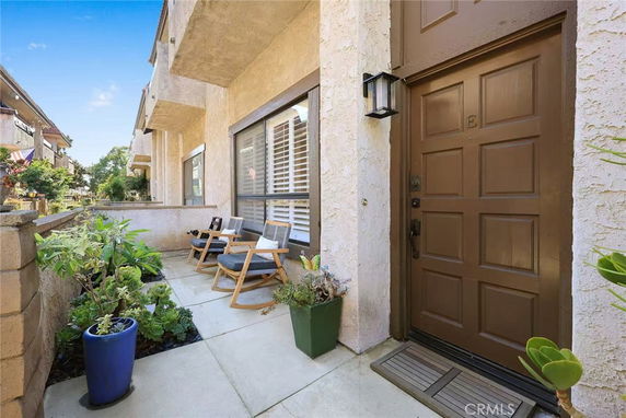 Front view of a house entrance with a small patio area and seating.