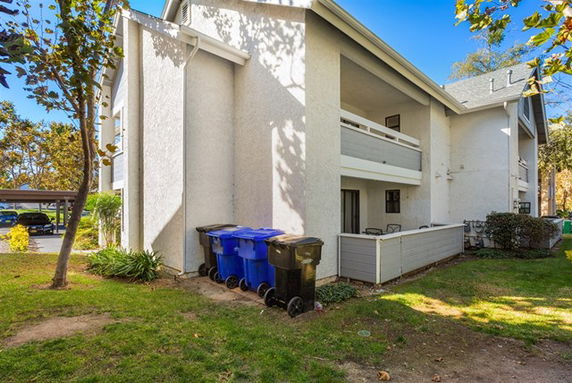 Side view of a two-story residential building with balconies and a sloped roof.