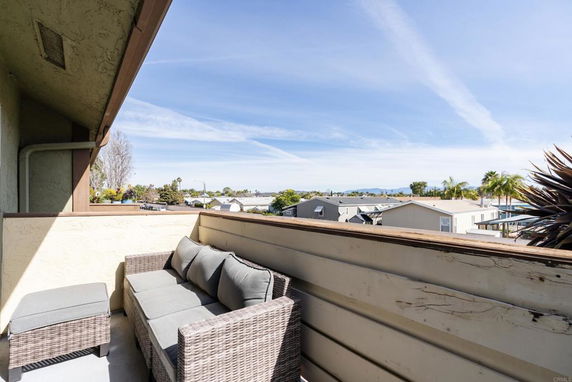 Balcony view overlooking residential area with distant hills.