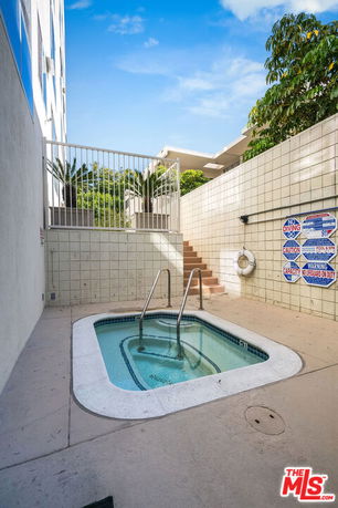 Small outdoor swimming pool area with tiled walls and safety signs.