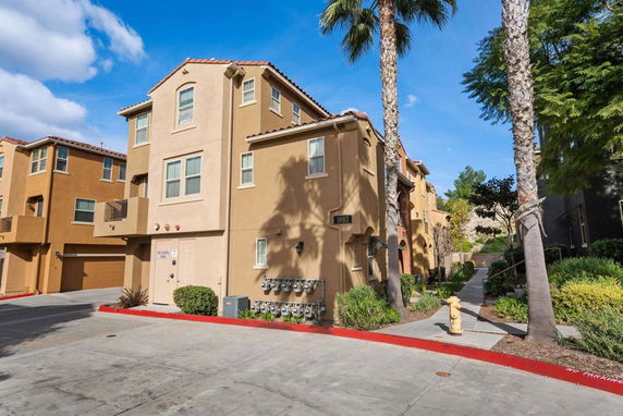 Front view of a multi-story residential building with beige exterior and garages.