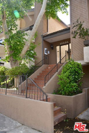 Front view of a multi-story building with stairs leading to the entrance.