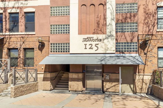 Front view of a multi-story building with brick and stucco exterior and a metal awning.
