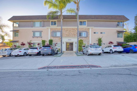 Front view of a three-story residential building with parking area.