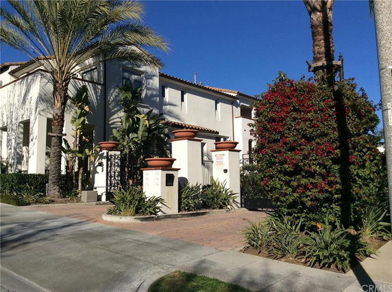 Front view of a two-story house with a tiled roof and gated entry.