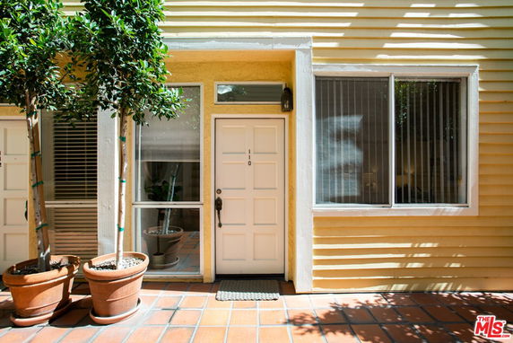 Front view of a house with a light-colored exterior and large windows.
