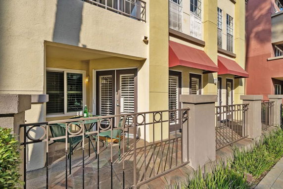 Front view of a multi-story building with a fenced patio and red awnings over the windows.