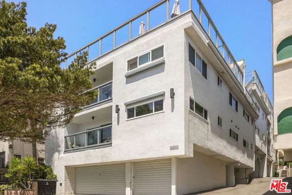 Front view of a multi-story building with a rooftop terrace and multiple balconies.