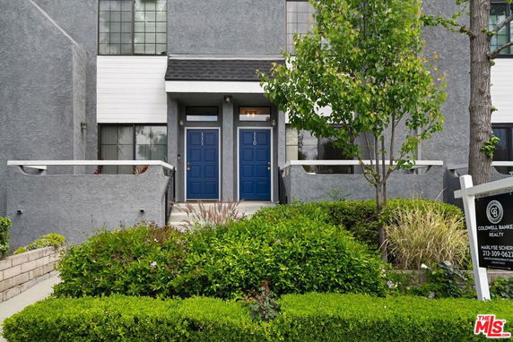 Front view of a building with two blue doors and grey exterior.
