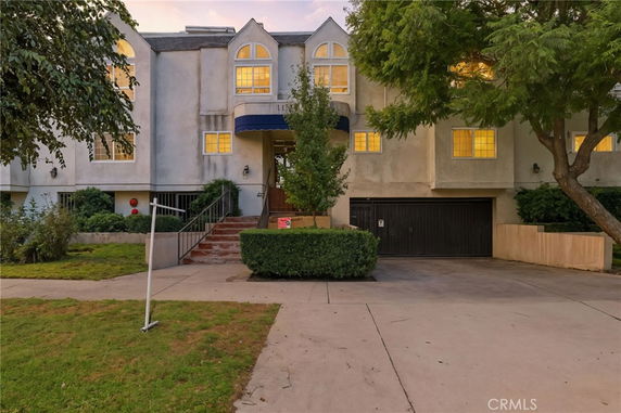Front view of a multi-story building with arched windows and a driveway.