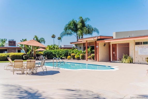Outdoor swimming pool area with surrounding chairs and a poolside building.