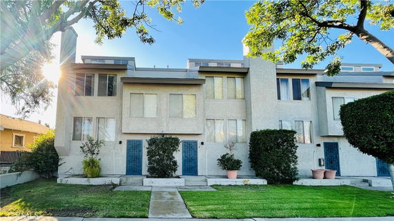Front view of a multi-story townhouse complex with small front gardens.